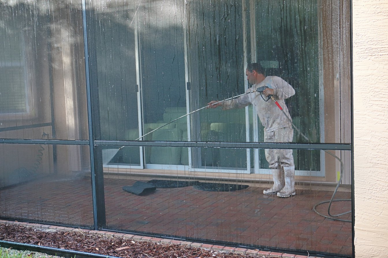 Series:Hispanic worker power washing screened in patio of home